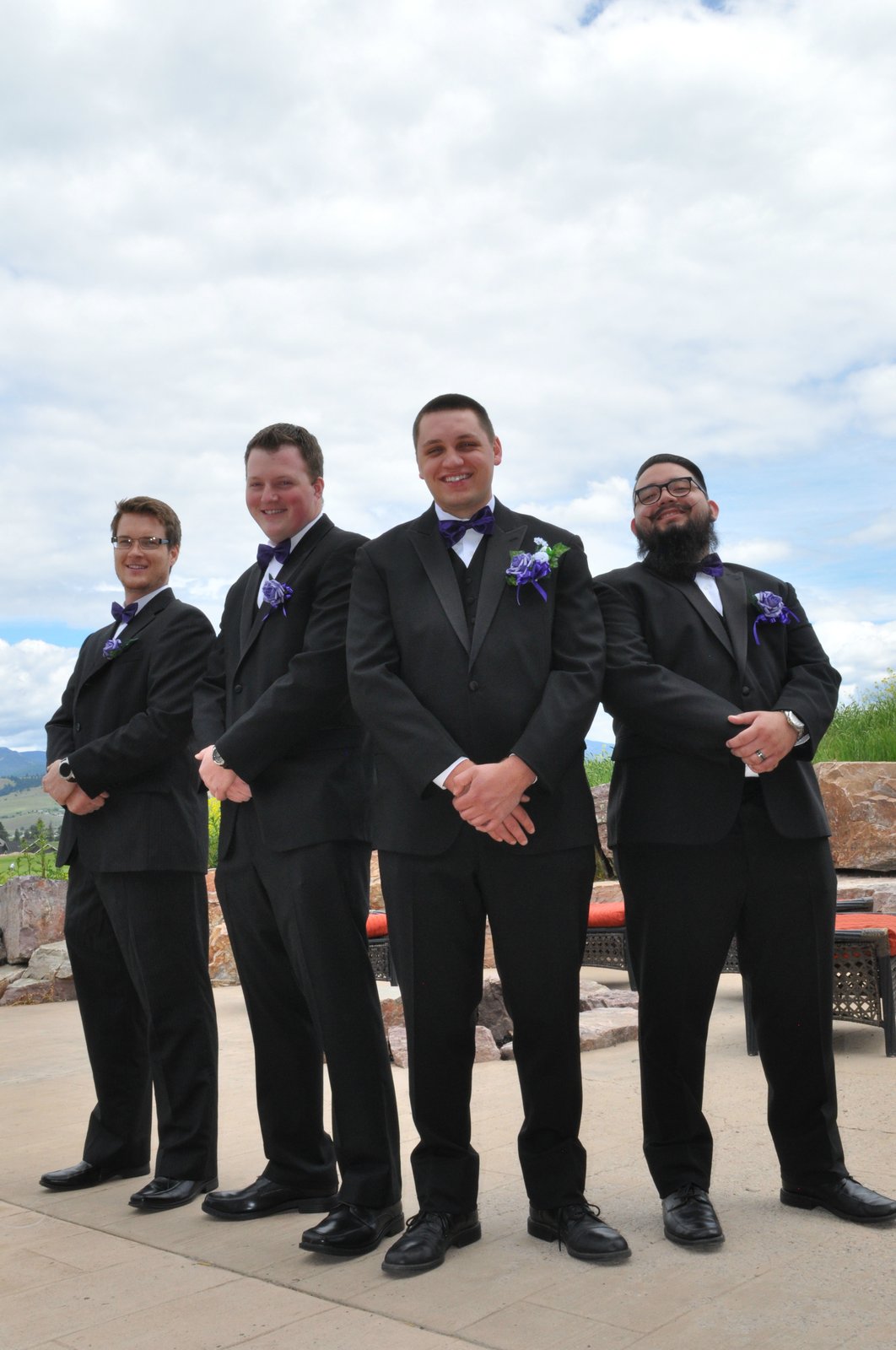 Groom and groomsmen in black tuxes with purple accents