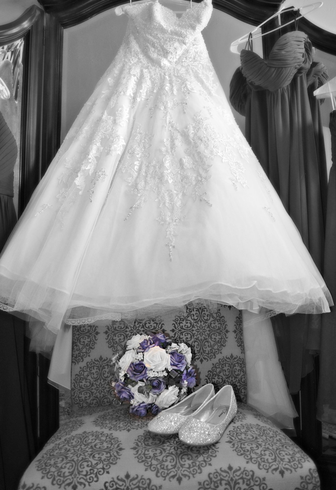 Lace wedding dress hanging above bouquet and glitter flats